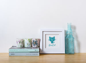Cat Design decor.  Blue cat in white frame on a wood shelf.